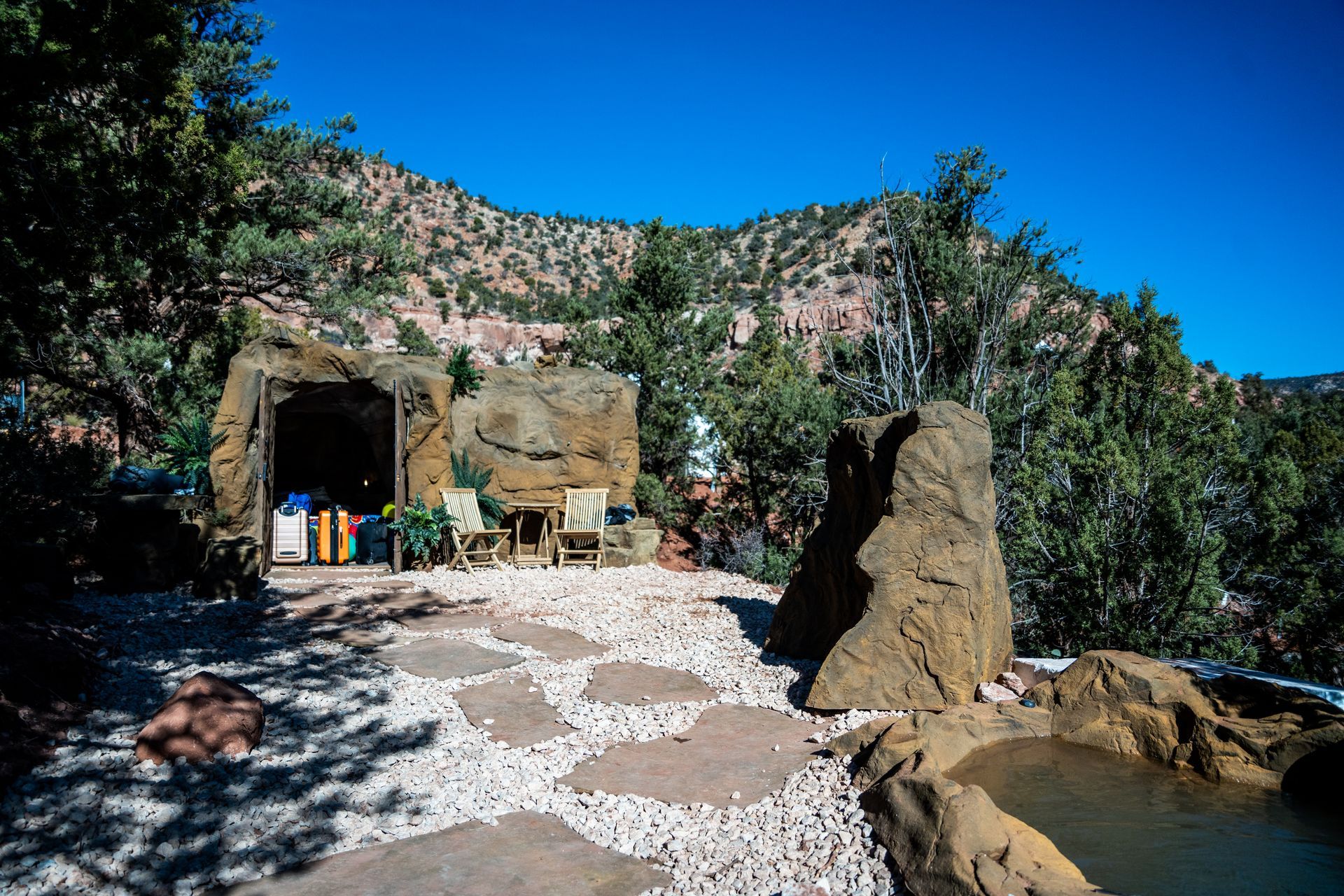 Outdoor seating area next to a rock hot tub with scenic views of mountains and trees near Zion Glamping Adventures.