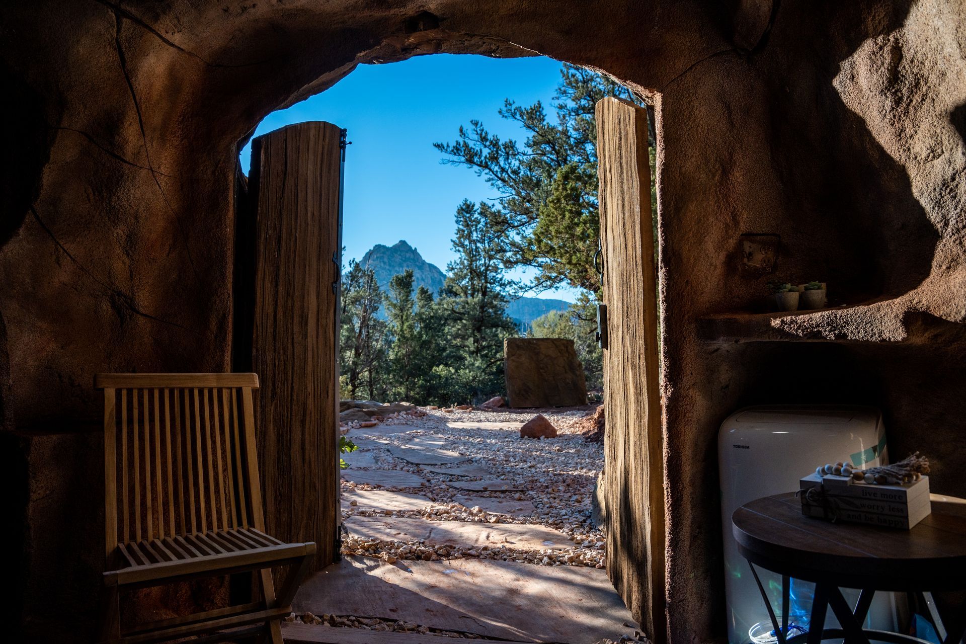 View from inside a rustic rock cabin looking through an open wooden door to the scenic landscape at Zion Glamping Adventure