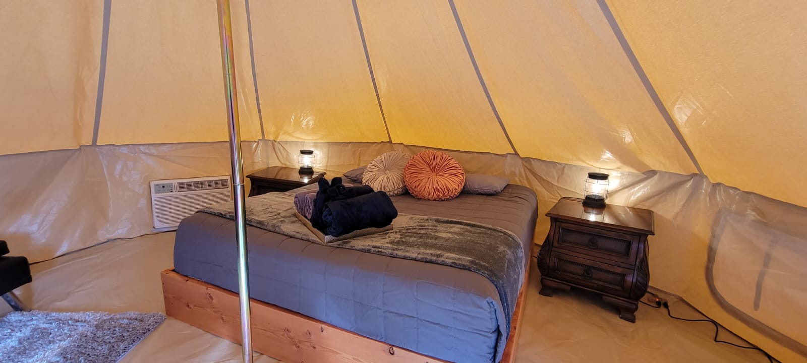 Interior of a glamping tent with a cozy bed, side tables, and warm lighting at Zion Glamping Adventures.