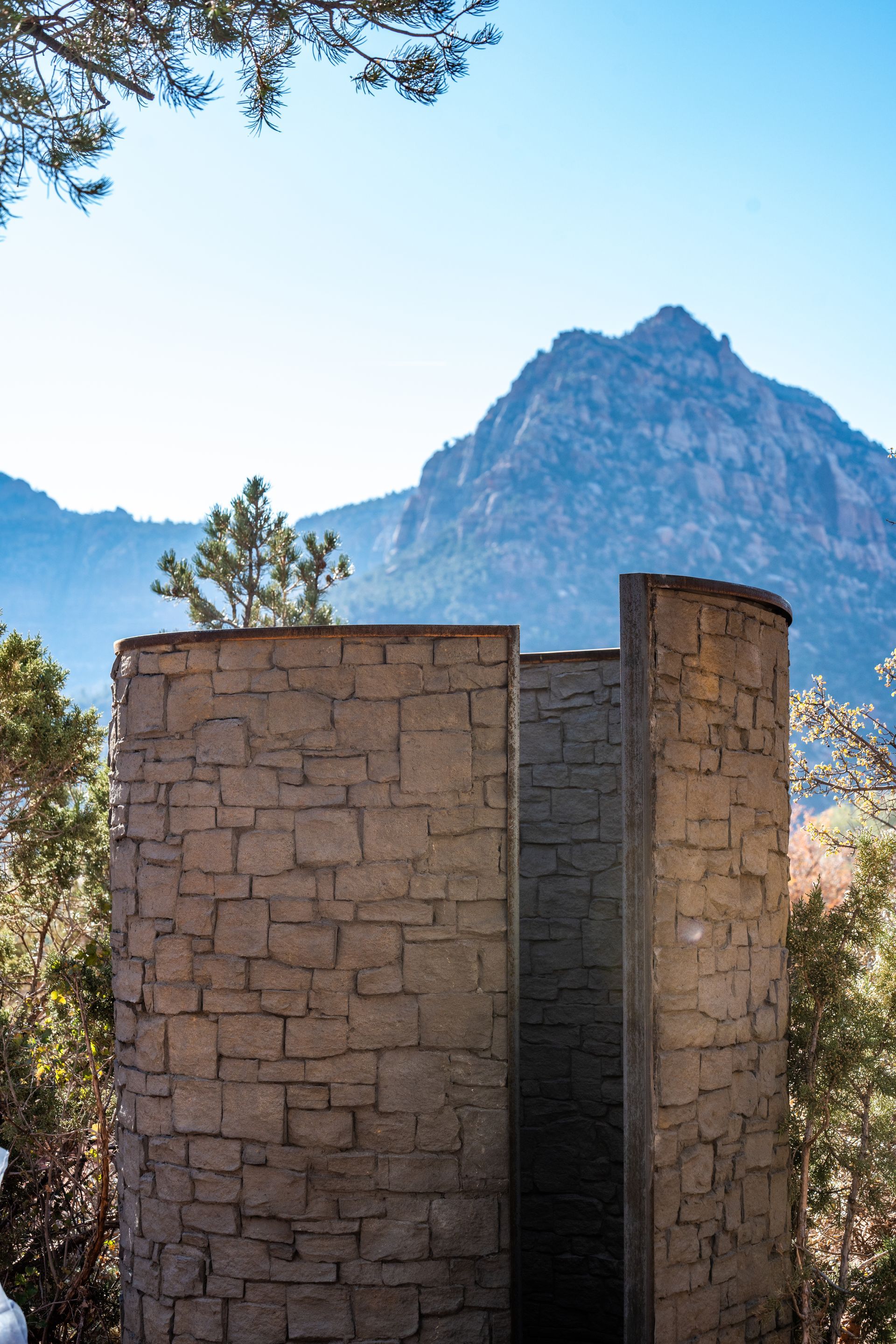 An outdoor shower with stone walls and a view of the mountains, providing a rustic yet modern bathing experience.