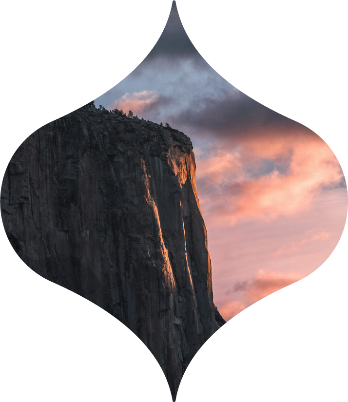 Rock cliff at sunset framed in a teardrop-shaped cutout against pink and gray clouds