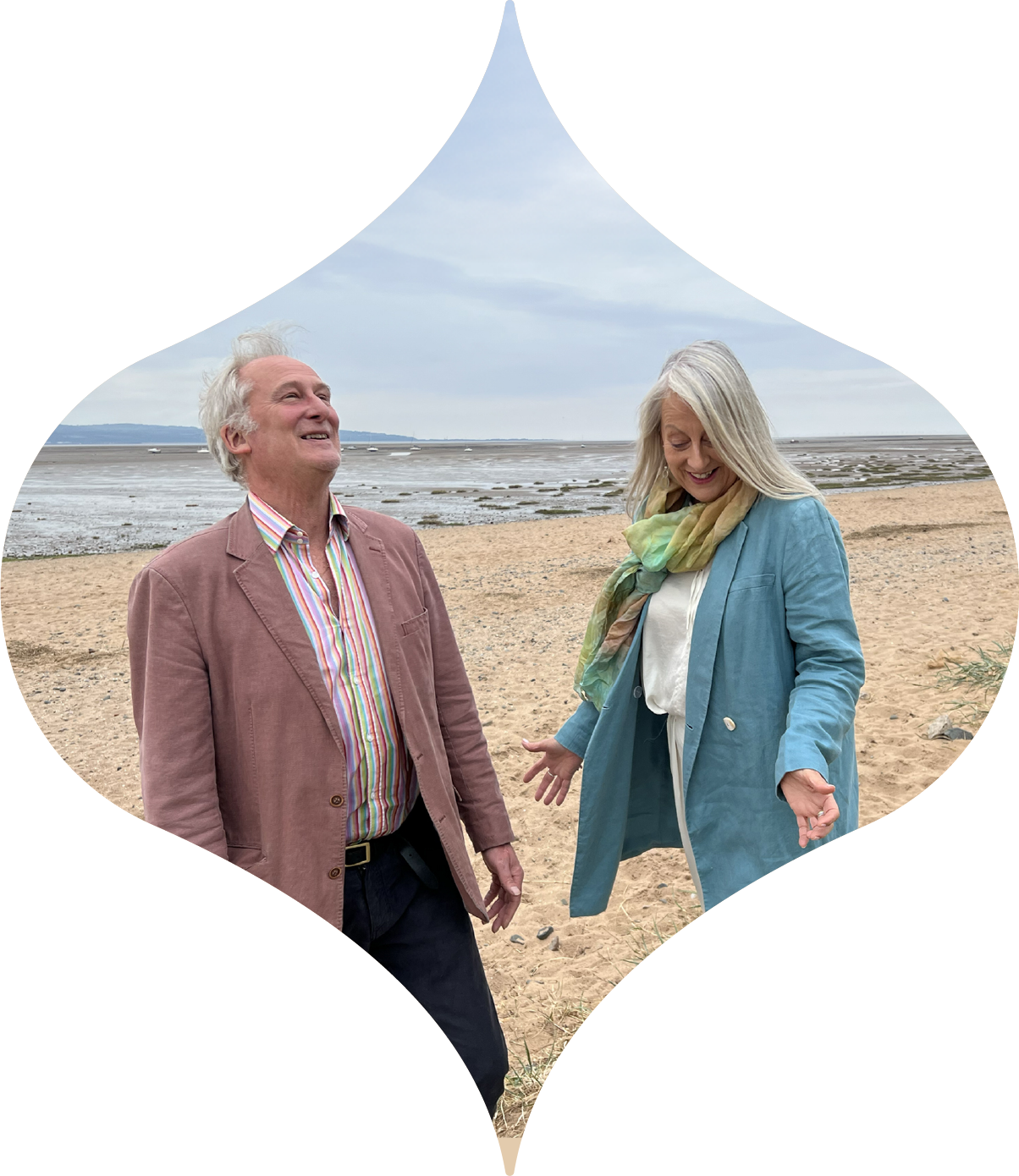 Two people smiling on a beach, with waves in the background and a decorative white border.