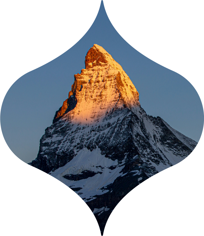 Snow-capped mountain peak lit by sunset, framed inside a blue droplet shape