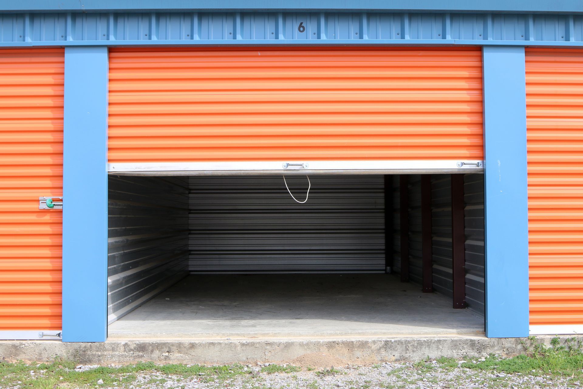 Orange Storage Unit With Partially Open Door, Blue Trim, and Concrete Base — Gympie Southside Mini Storage in Southside, QLD