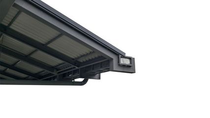 A close-up view of the underside of a dark gray metal roof overhang featuring a rectangular outdoor light fixture.