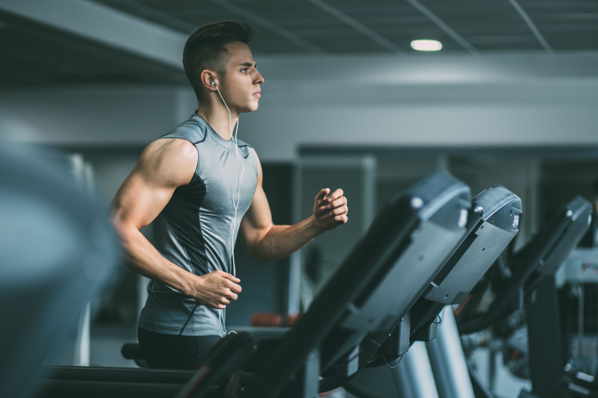 Man running on a treadmill at a gym, wearing a gray workout shirt. Man running on a treadmill at a gym, wearing a gray workout shirt.