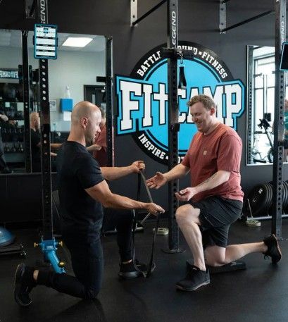 Shirtless person using battle ropes in a gym, legs bent, focused expression. Shirtless person using battle ropes in a gym, legs bent, focused expression.