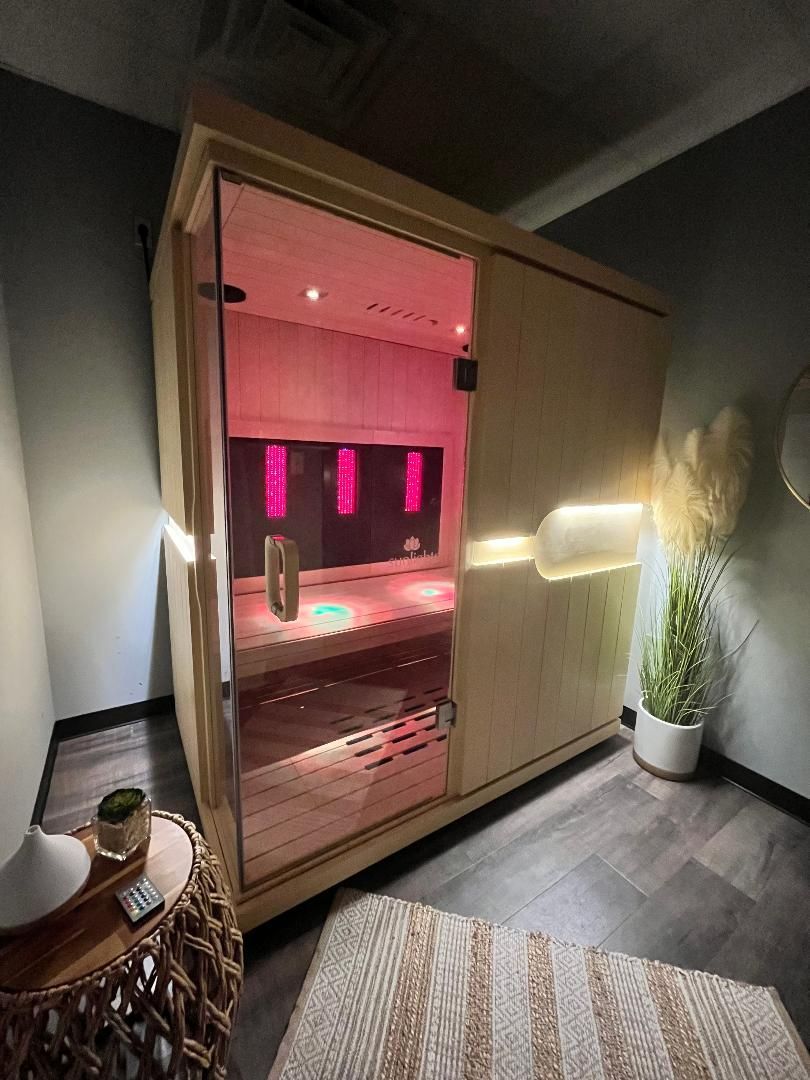 A modern wooden home sauna with a glass front, glowing pink interior lighting, and ambient LED wall accents in a room. A modern wooden home sauna with a glass front, glowing pink interior lighting, and ambient LED wall accents in a room.