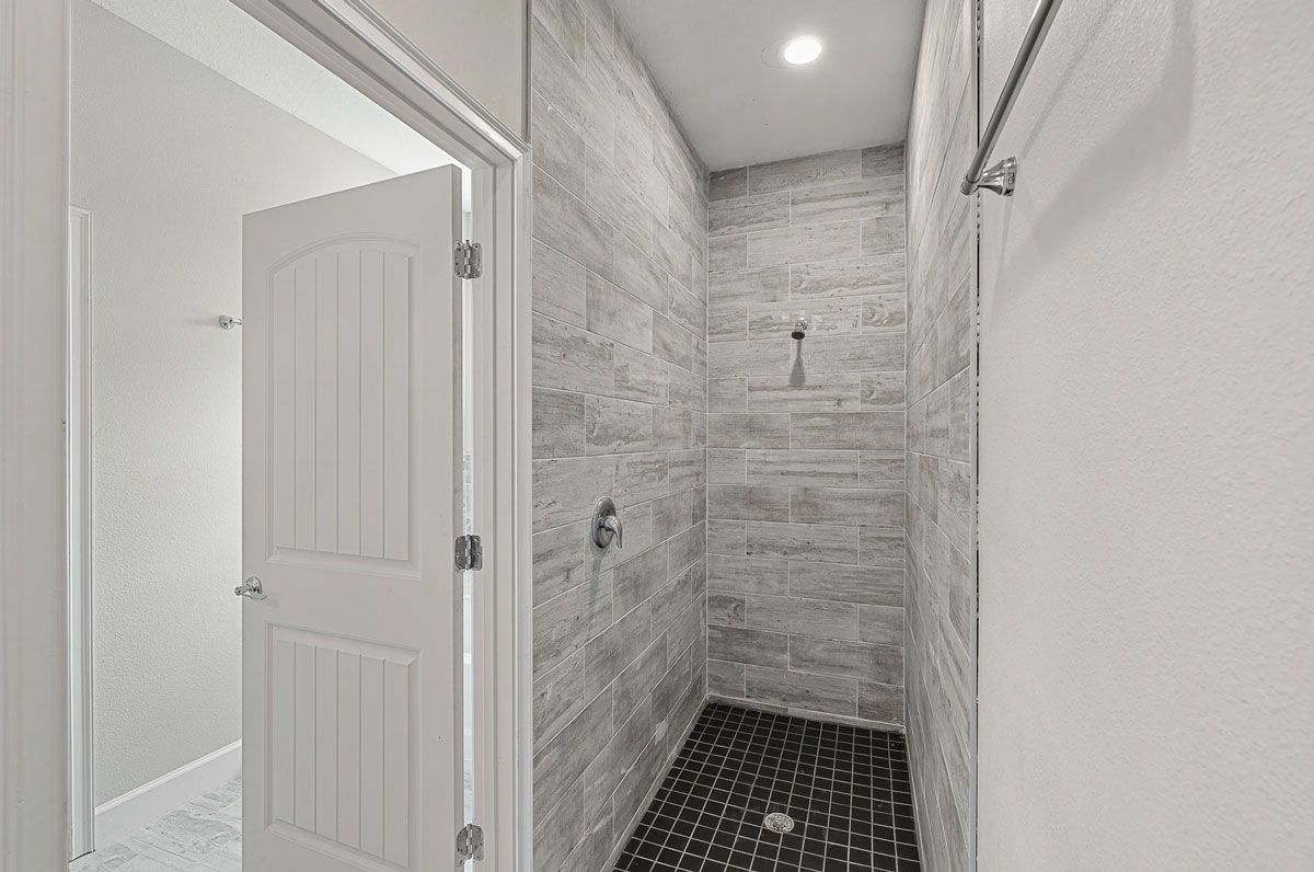 A bathroom with a walk in shower and a white door.