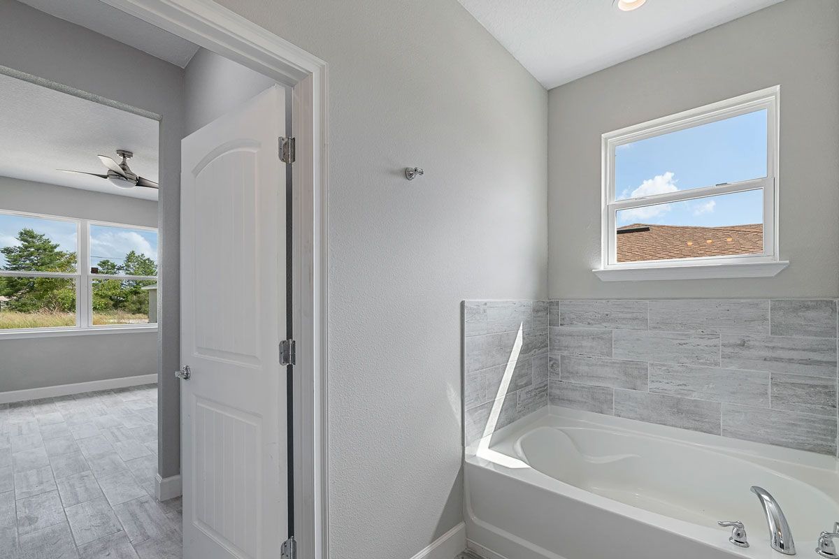 A bathroom with a bathtub and a window.