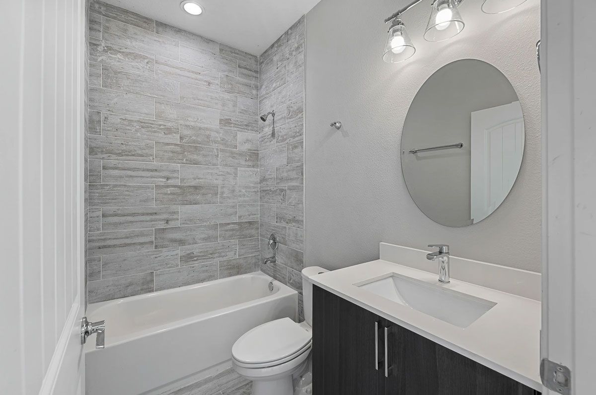A bathroom with a toilet , sink , bathtub and mirror.