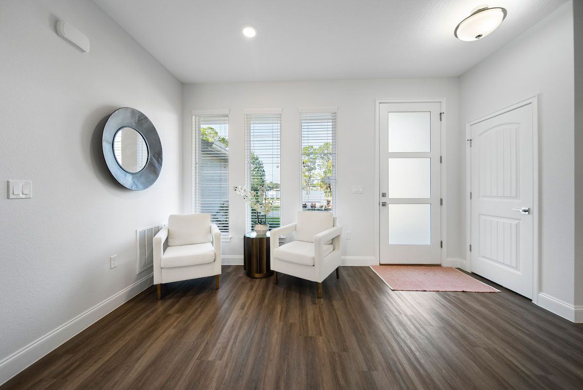 A living room with two chairs and a mirror on the wall.
