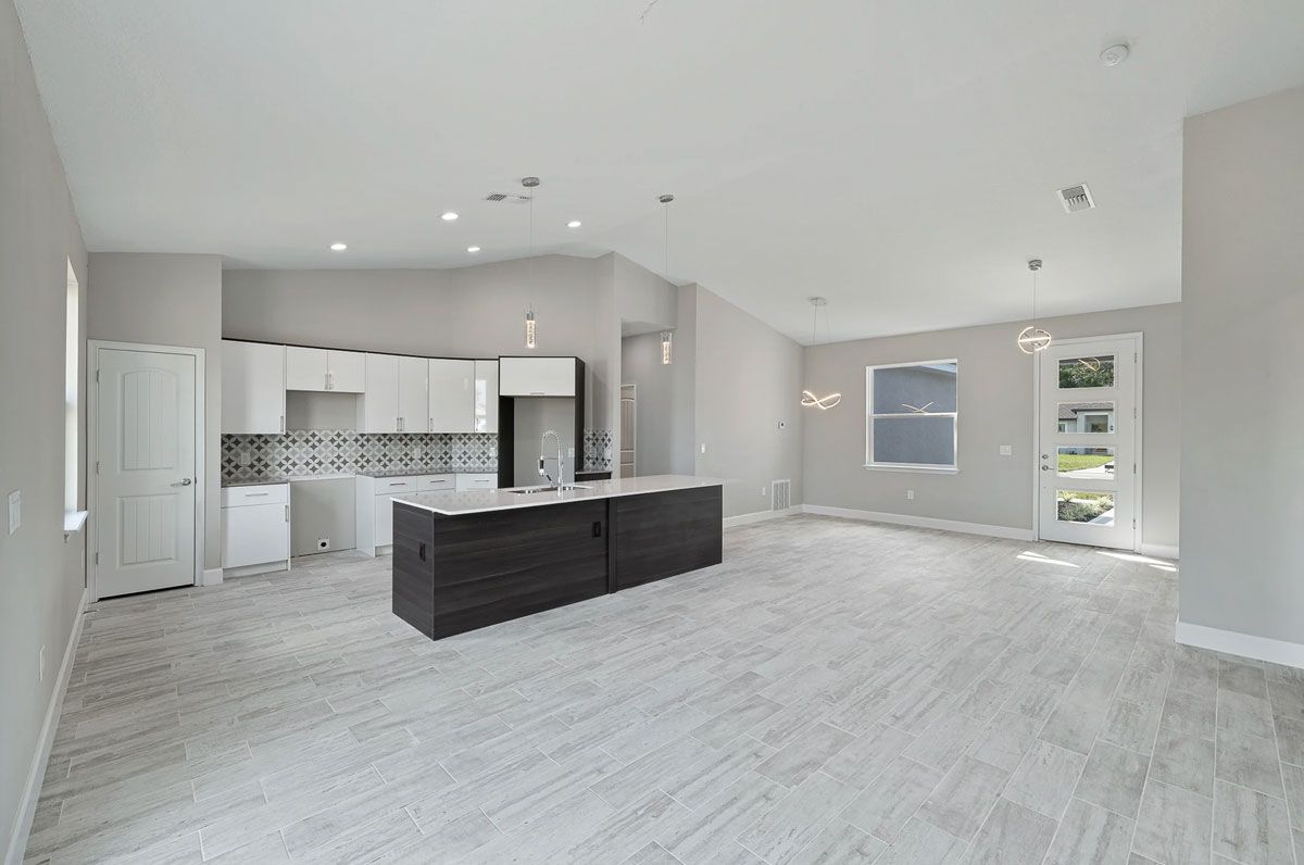 A large empty room with a kitchen and a large island in the middle.