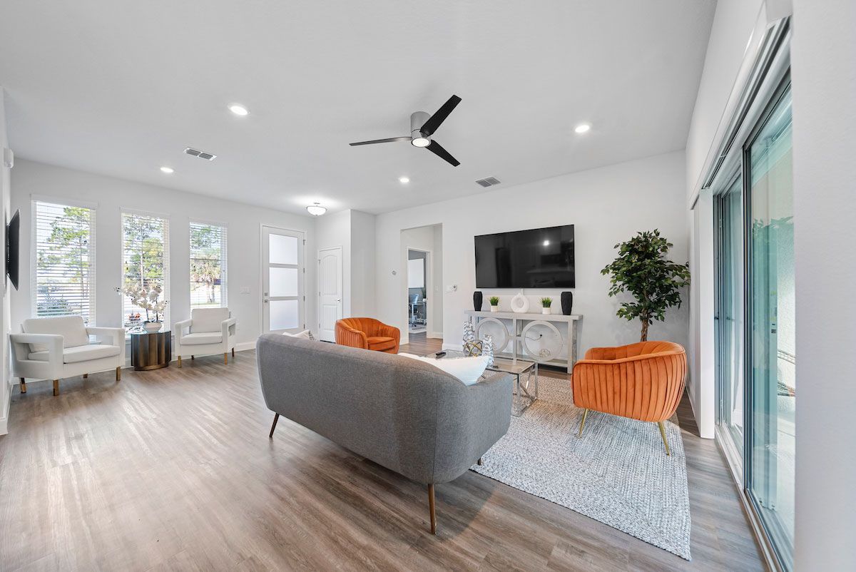 A living room with a couch , chairs , a television and a ceiling fan.