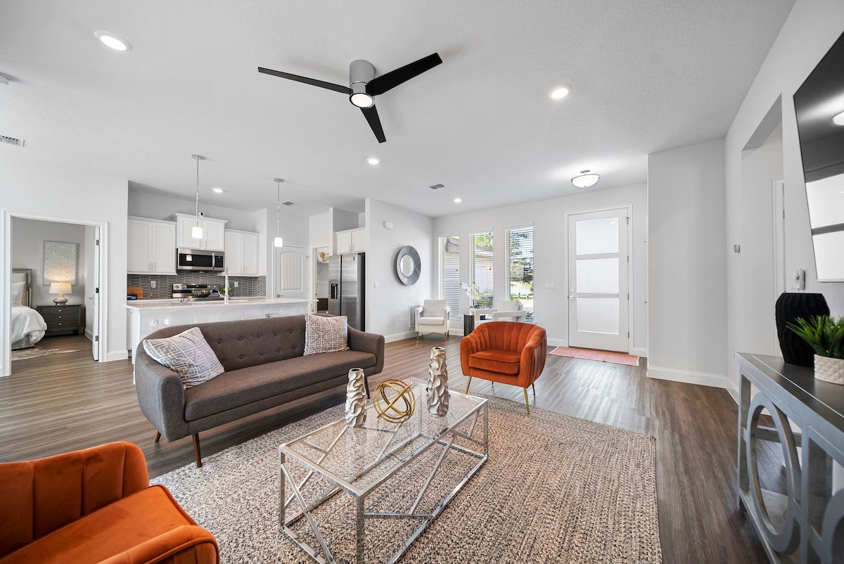 A living room with a couch , chairs , coffee table and ceiling fan.