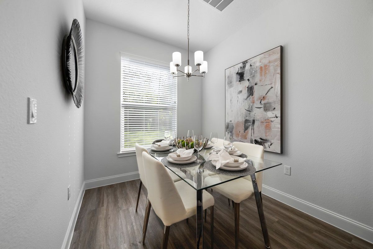 A dining room with a glass table and chairs and a painting on the wall.