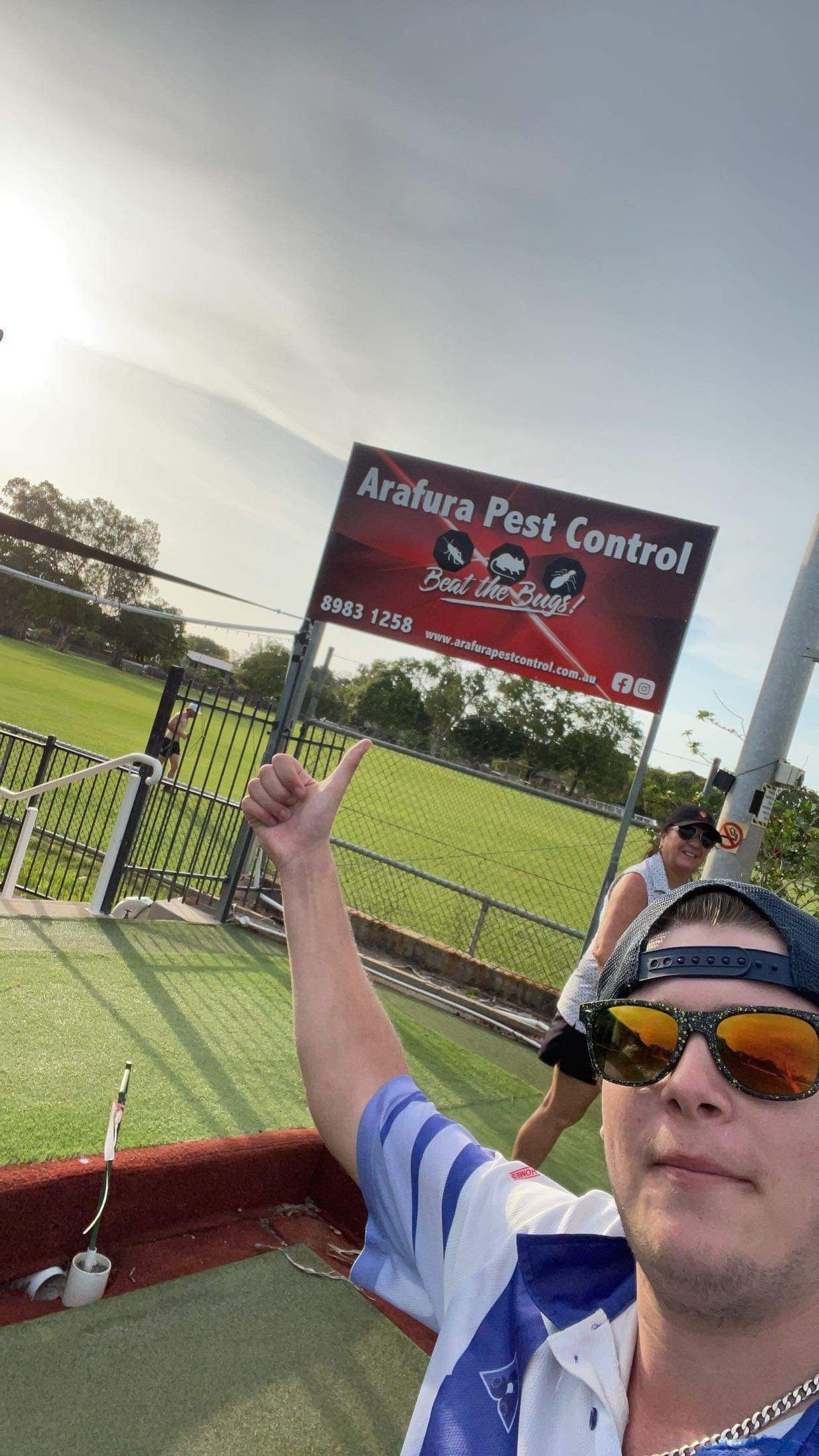 A Man Is Spraying Water On A Lawn With A Sprayer — Arafura Pest Control Darwin In Yarrawonga, NT