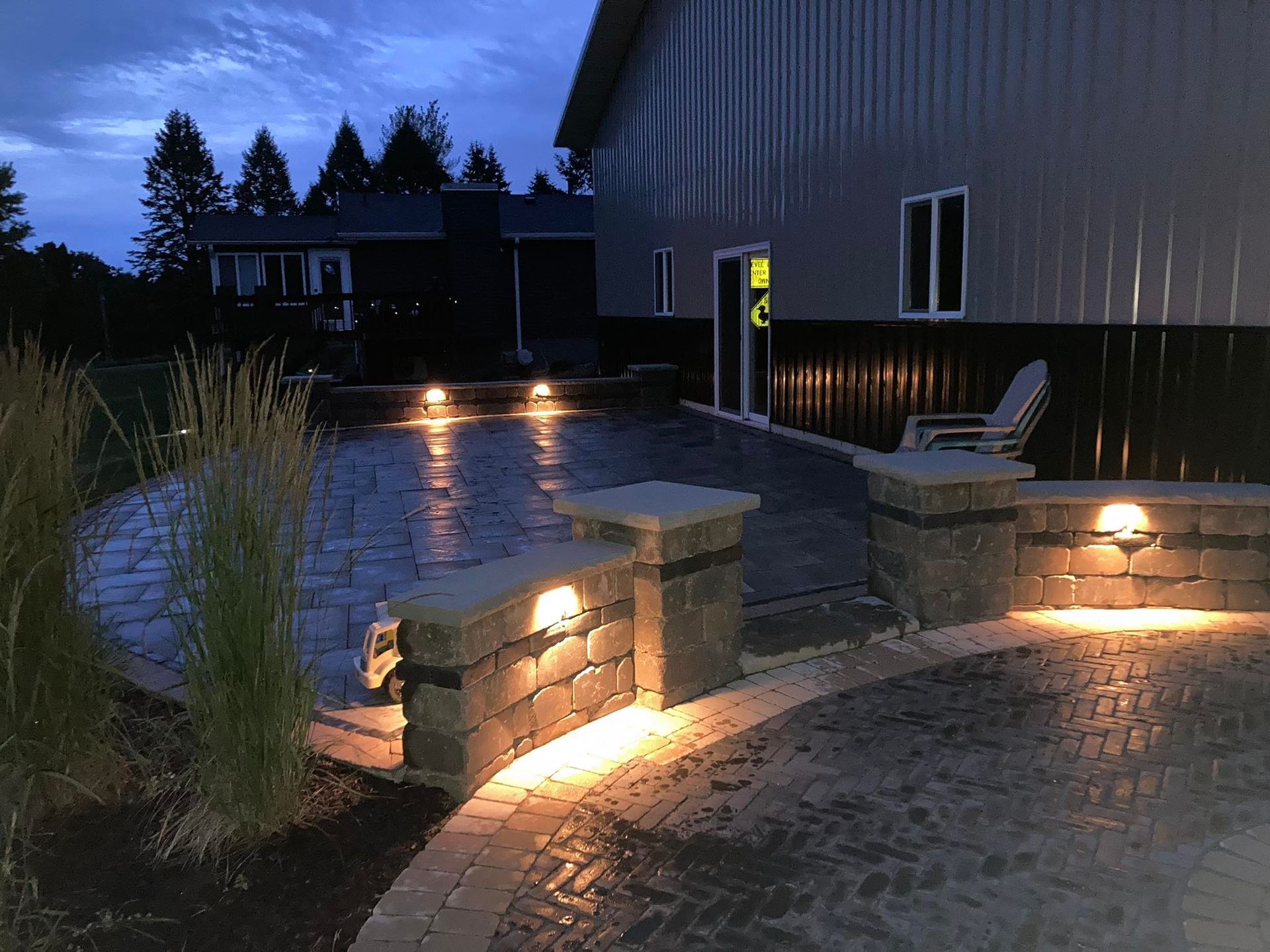 Nighttime view of a brick patio with built-in lighting beside a building with a dark exterior.