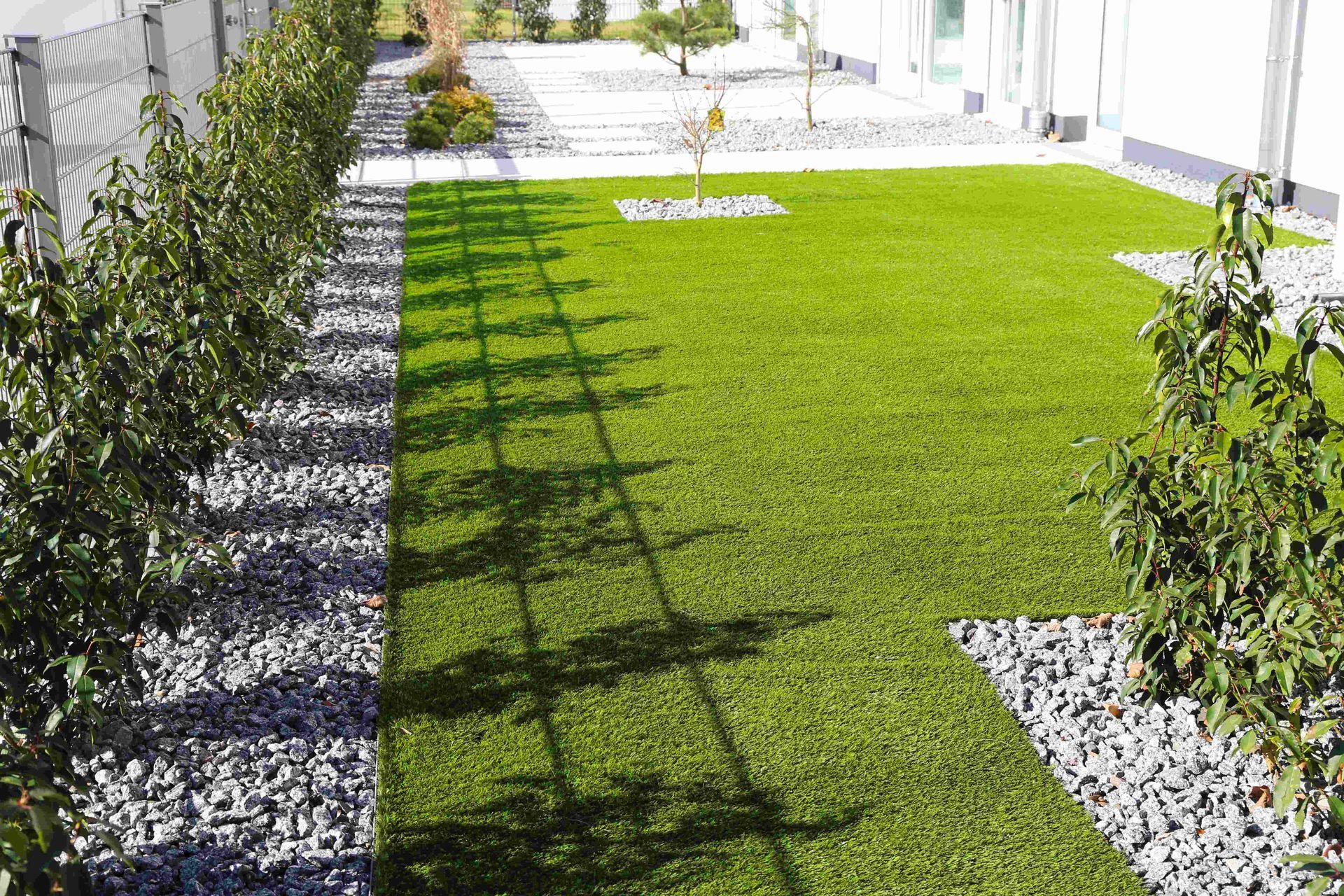 a lush green lawn surrounded by bushes and gravel in a backyard