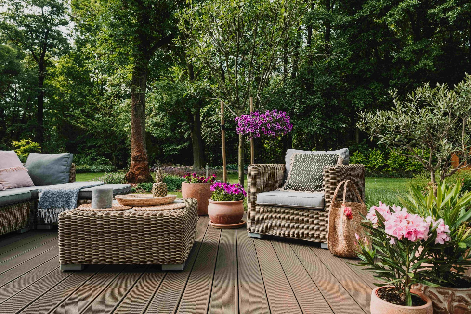 a wooden deck with wicker furniture and potted plants