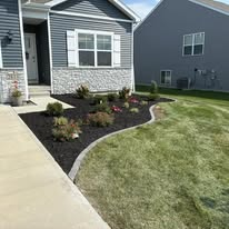 Front view of a house with mulch landscaping, green grass, and a concrete pathway.