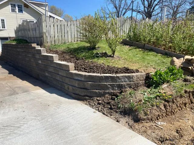 a stone wall is being built in the backyard of a house