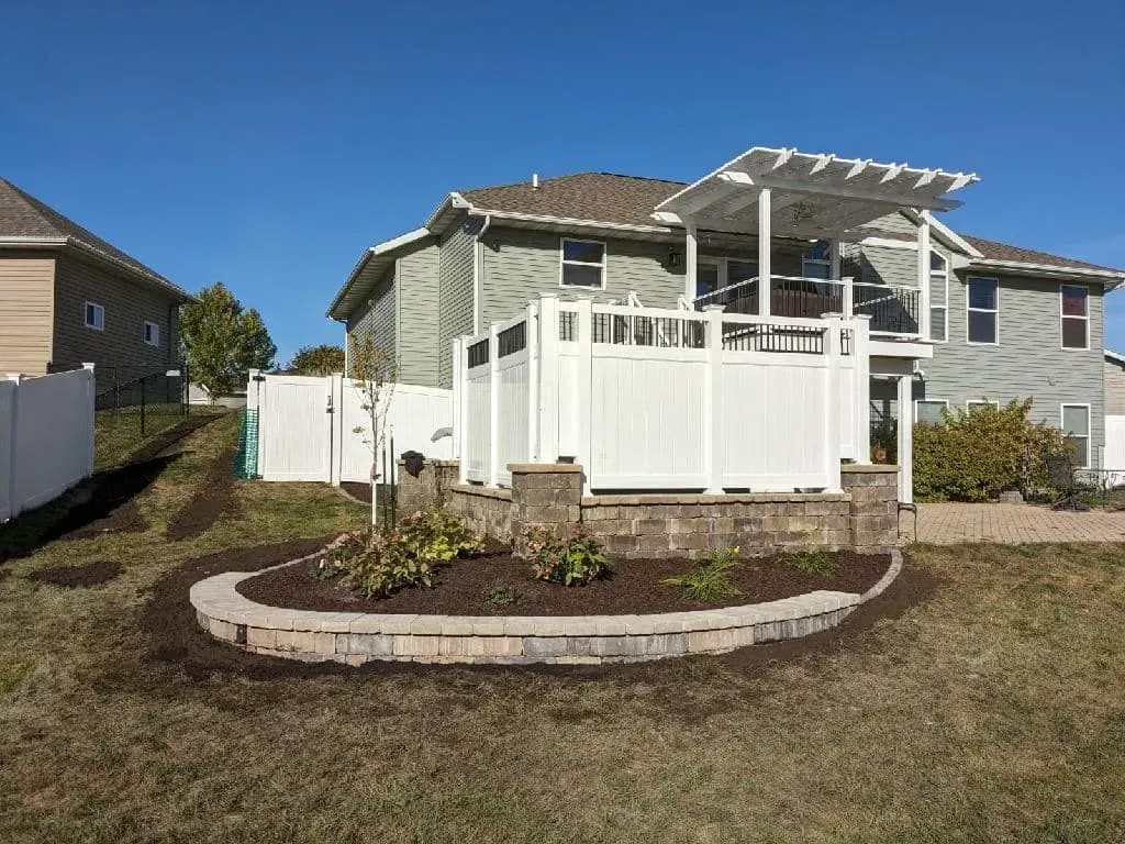a house with a white fence and a pergola in the backyard