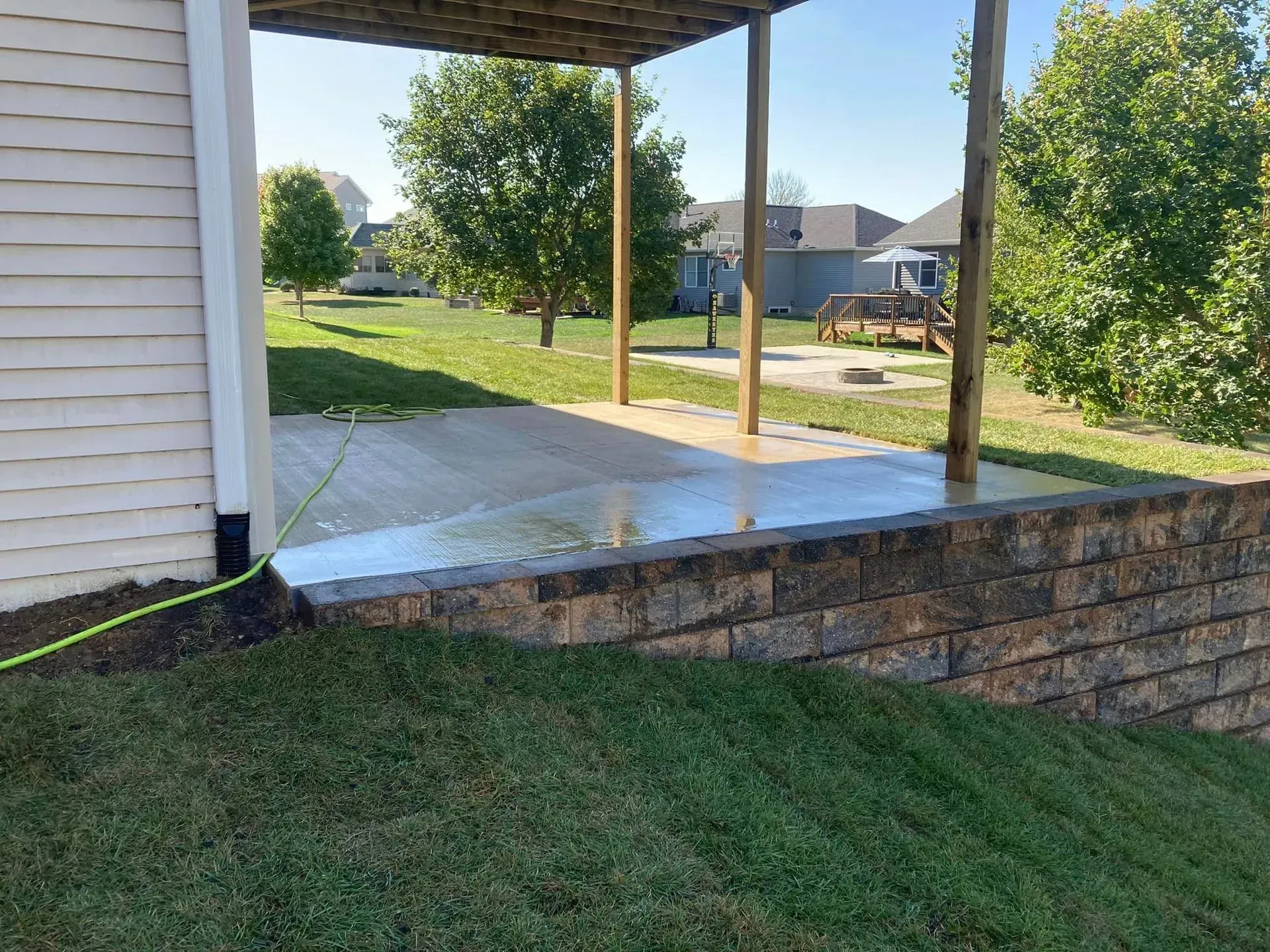a patio with a pergola and a brick wall in front of a house