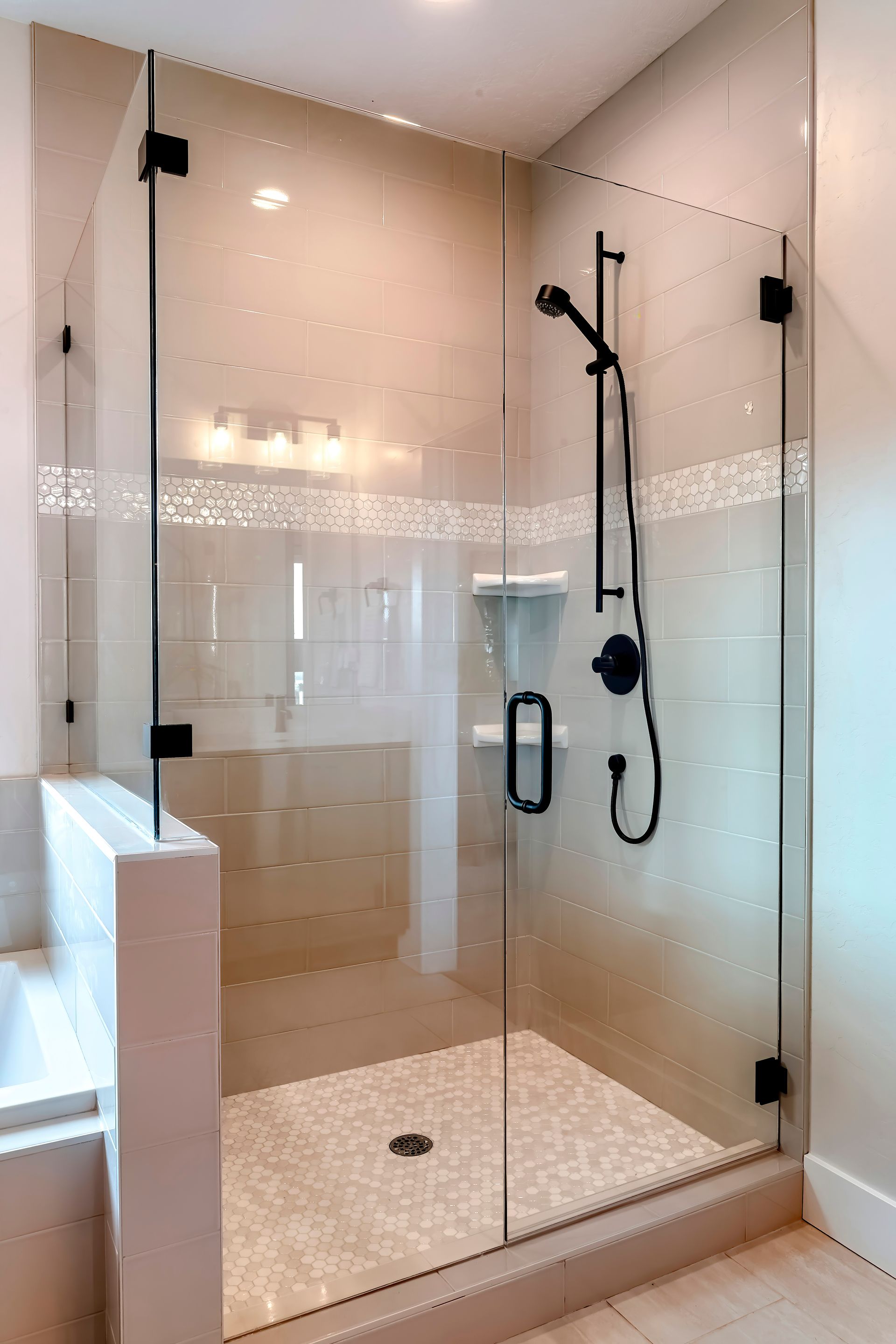 Shower stall with half glass enclosure and black shower fixtures.