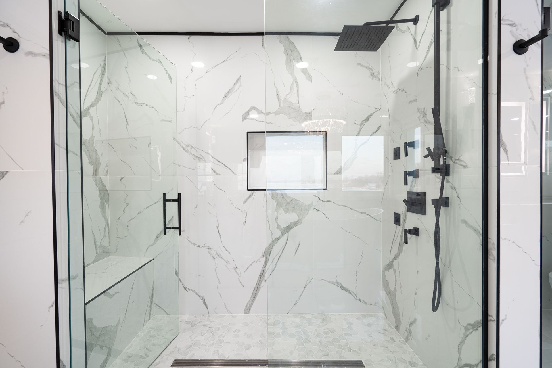 Sleek shower door installation on a modern frameless marble walk-in bathroom enclosure.