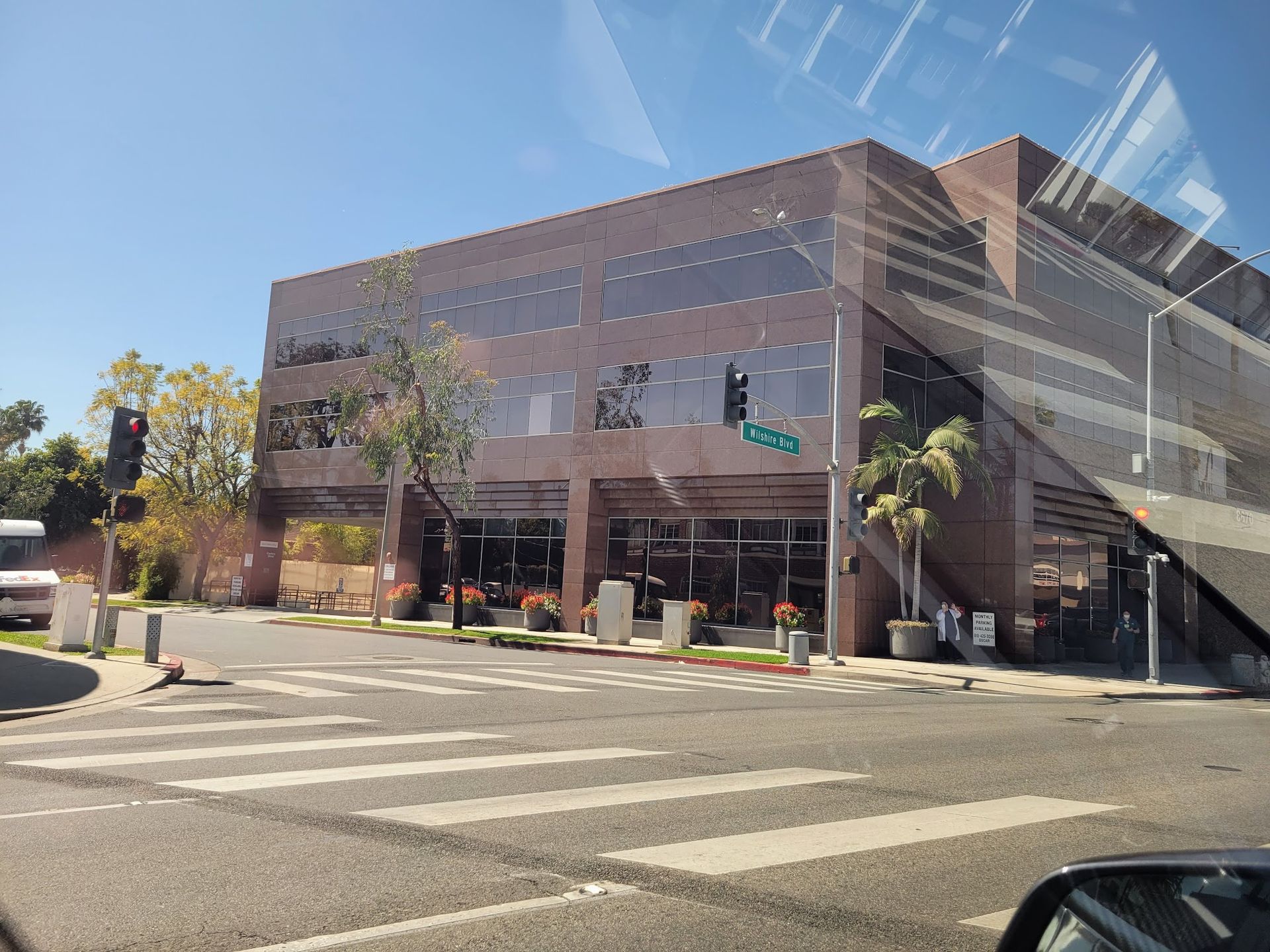 A multi-story, brown office building viewed from a street corner under a clear blue sky.