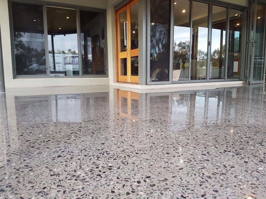 Polished aggregate concrete patio reflecting the glass doors and interior of a modern home.