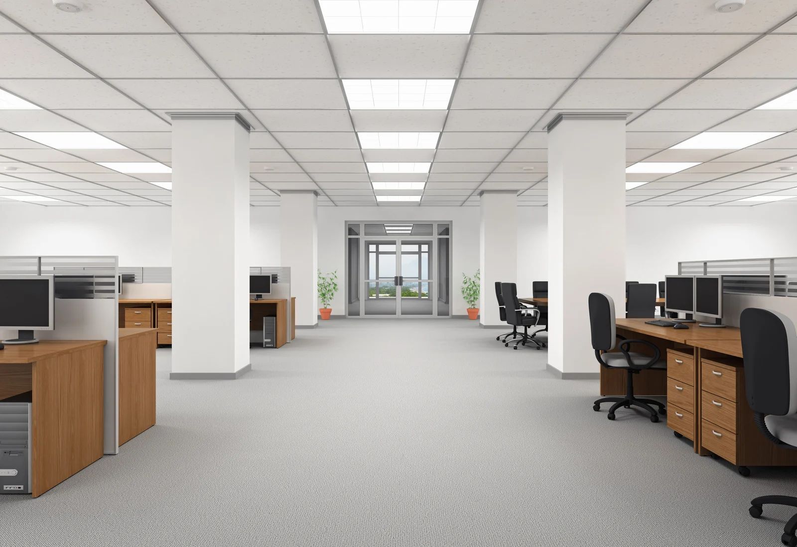 Modern open-plan office with desks, computers, and white columns under bright ceiling lights