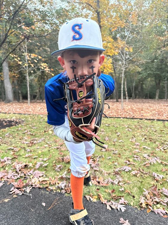 A young boy in a baseball uniform is holding a baseball glove.
