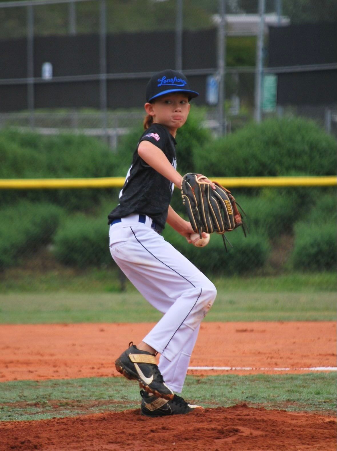 A young boy wearing a dodgers hat is playing baseball
