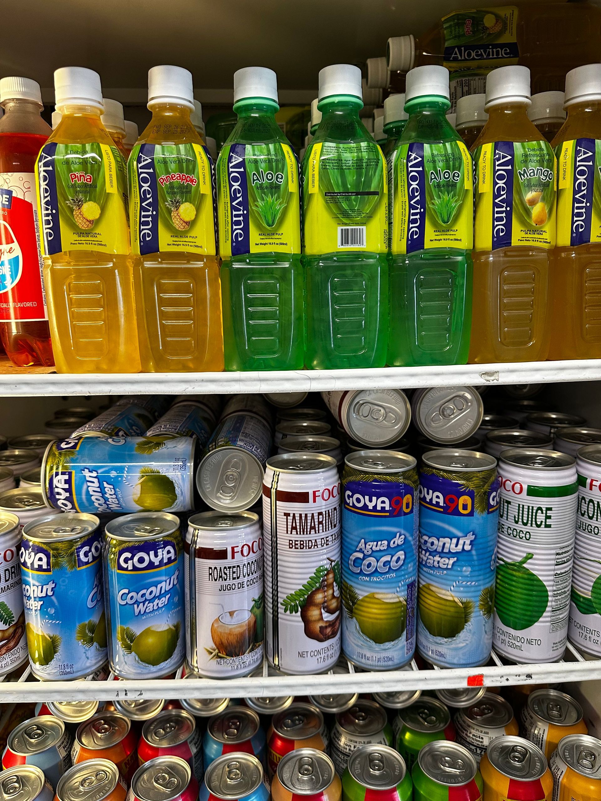 Shelf of colorful bottled drinks and canned beverages in a store display