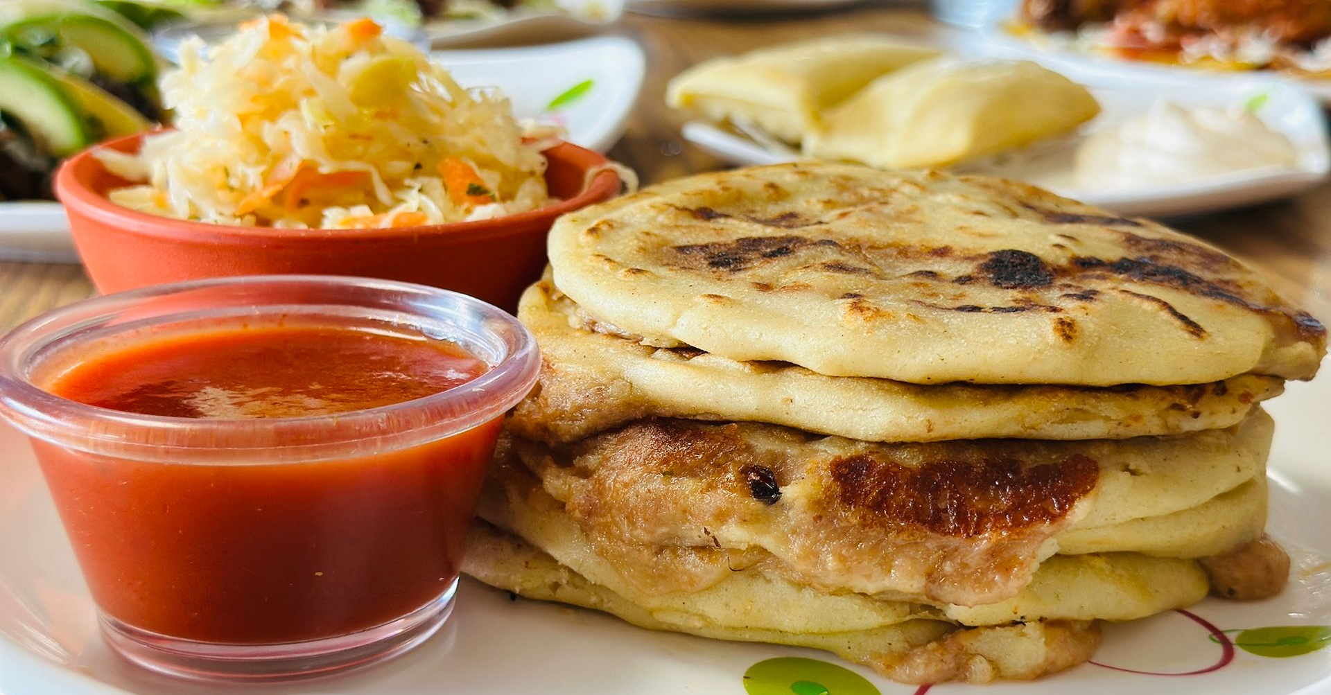 Stack of golden flatbreads with a cup of red sauce and a side of shredded salad.