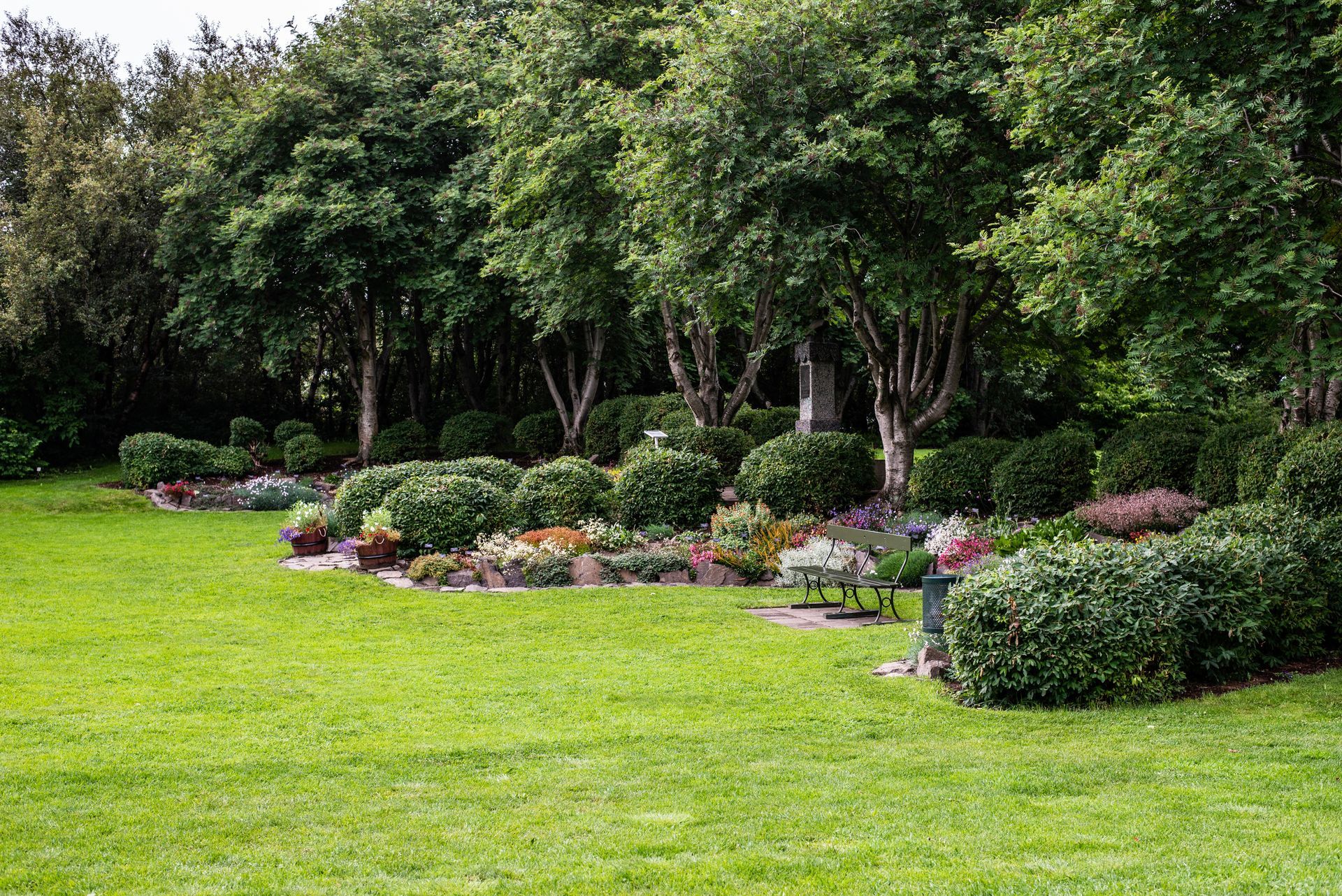 A lush green lawn surrounded by trees and bushes in a park.