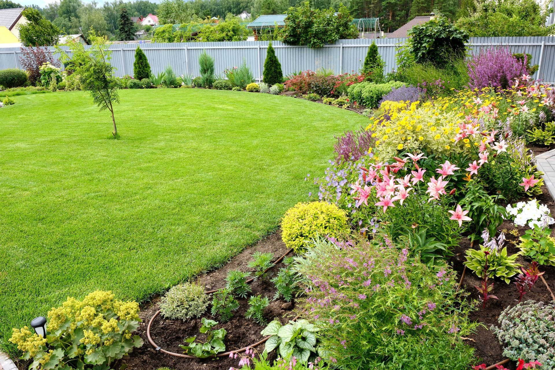 A garden with lots of flowers and a lush green lawn.
