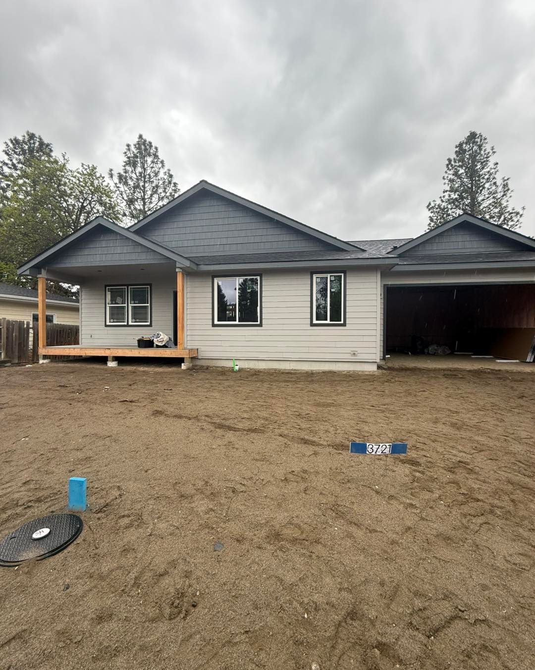 New construction house with gray roof, beige siding, and bare yard.