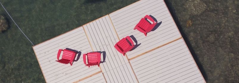 A group of red chairs are sitting on top of a wooden deck.