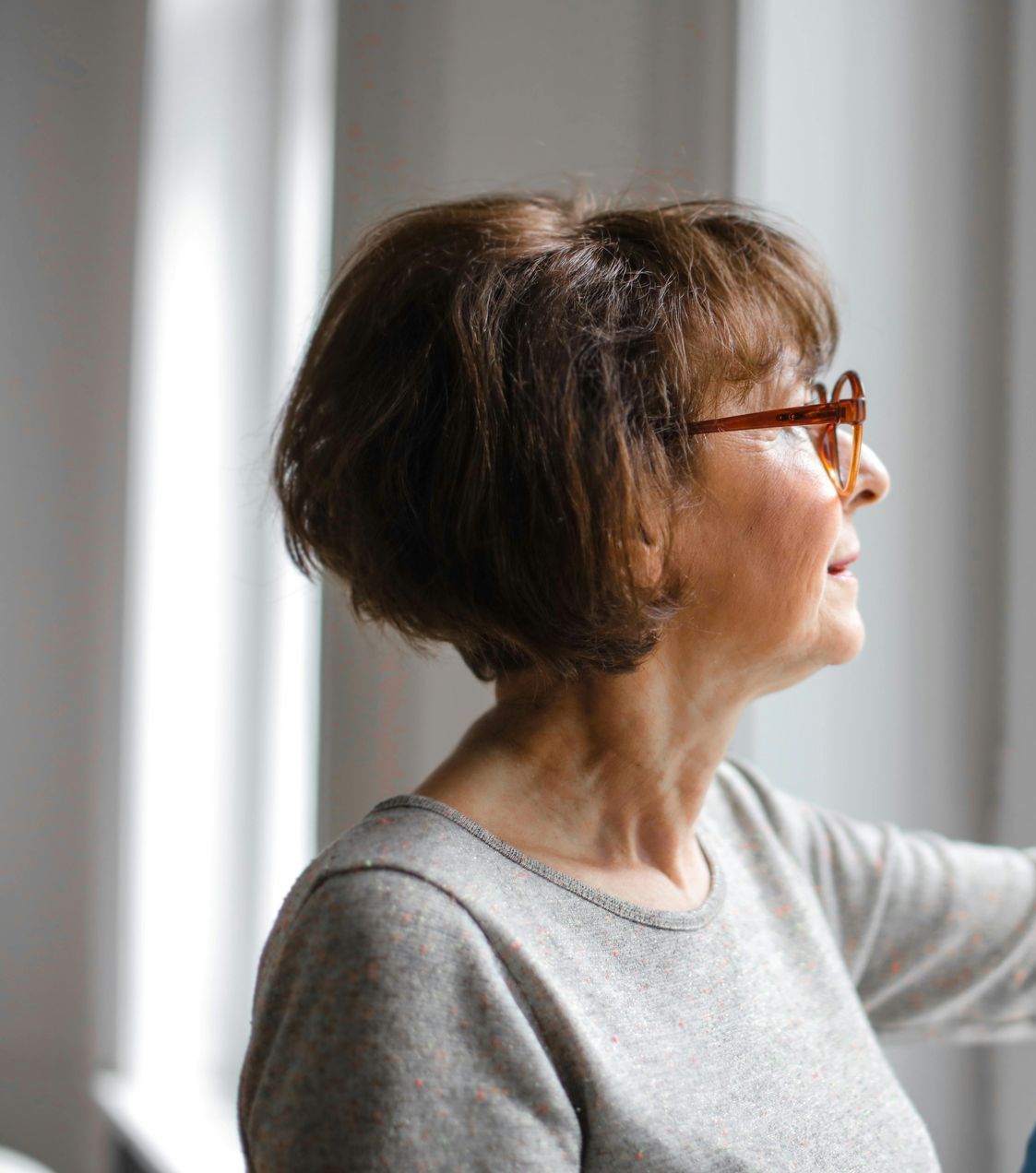 A woman wearing glasses is looking out a window