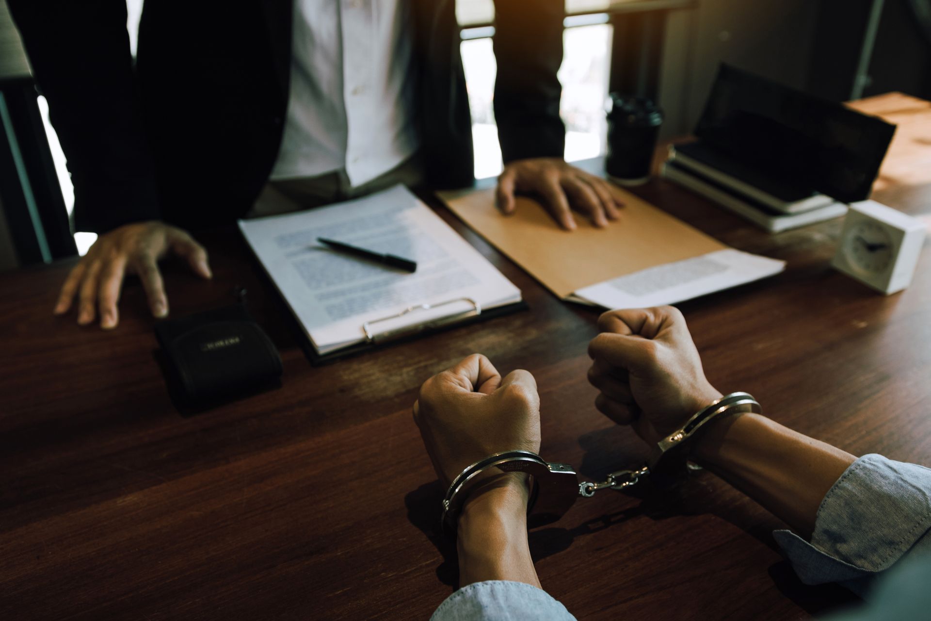 A man in handcuffs is sitting at a table with a lawyer.