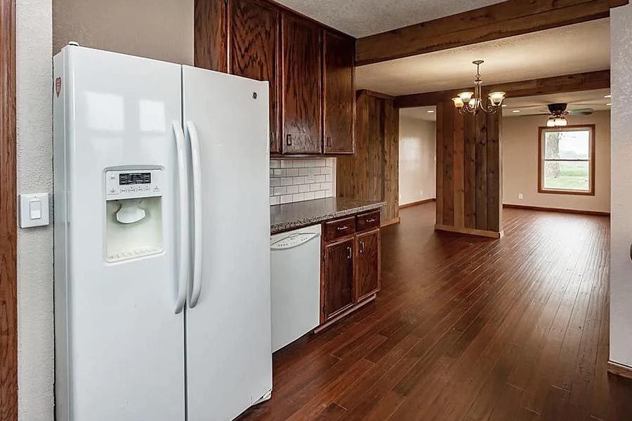 A kitchen with hardwood floors and a white refrigerator.