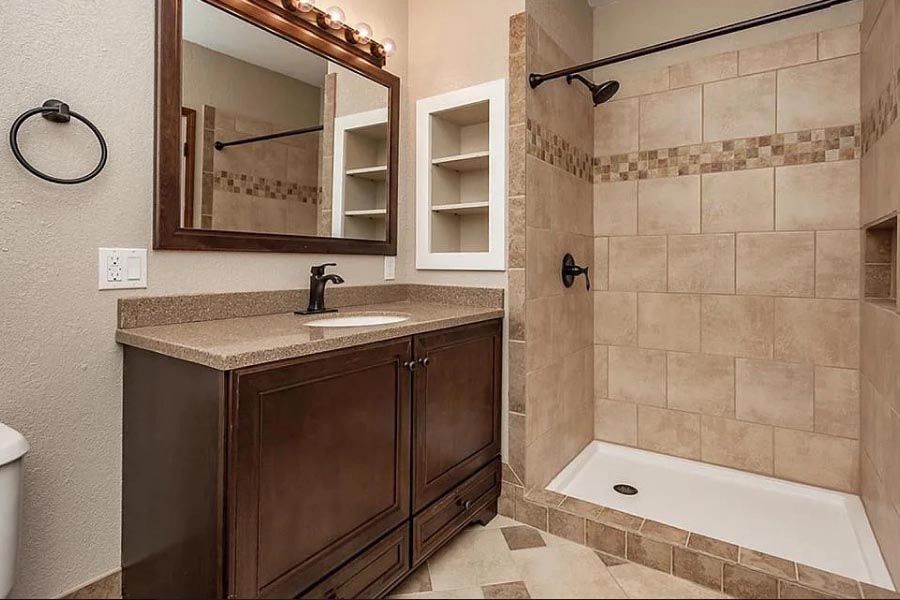 A bathroom with a sink , mirror , and walk in shower.