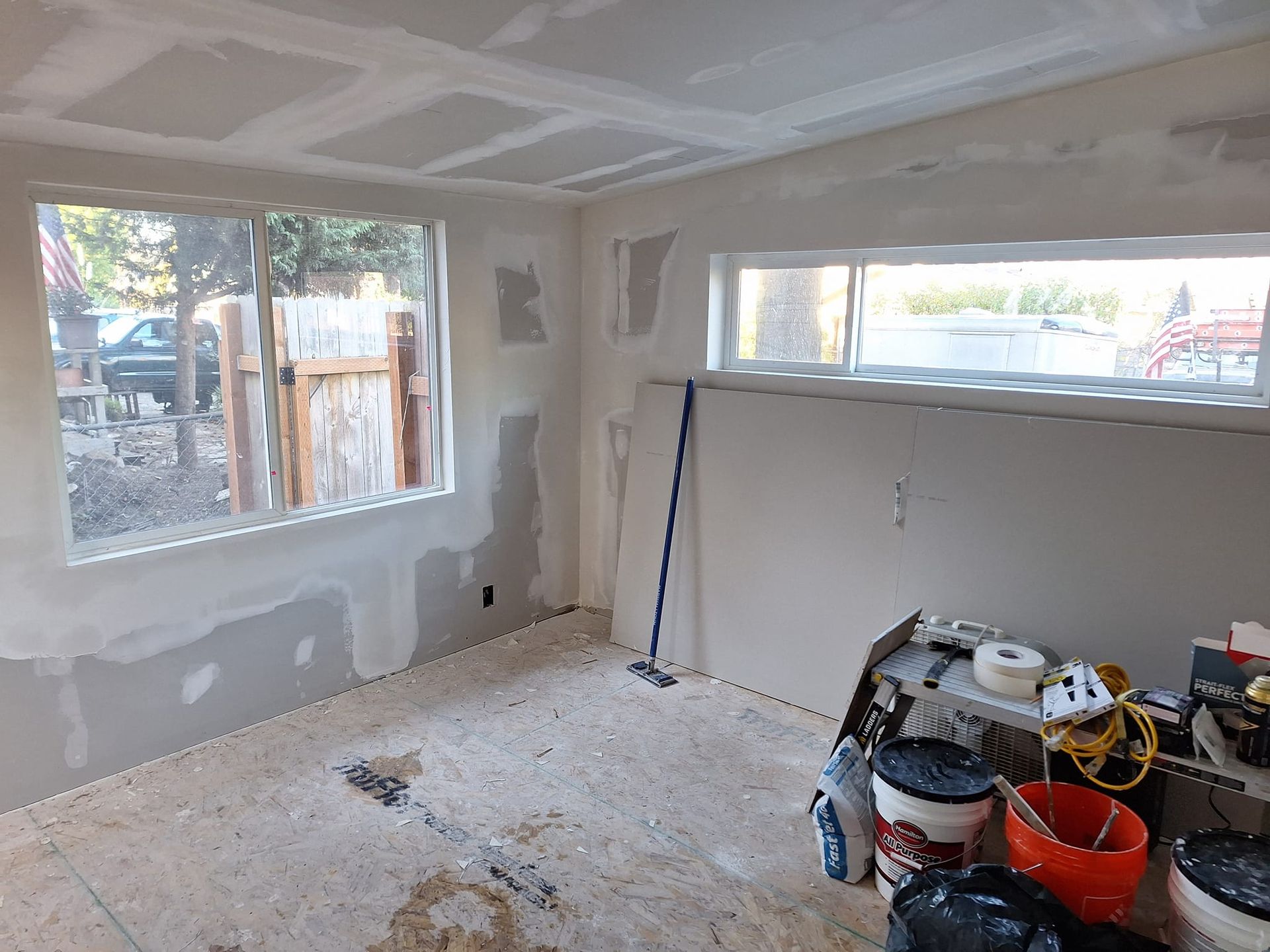 A room with a window and buckets of paint on the floor