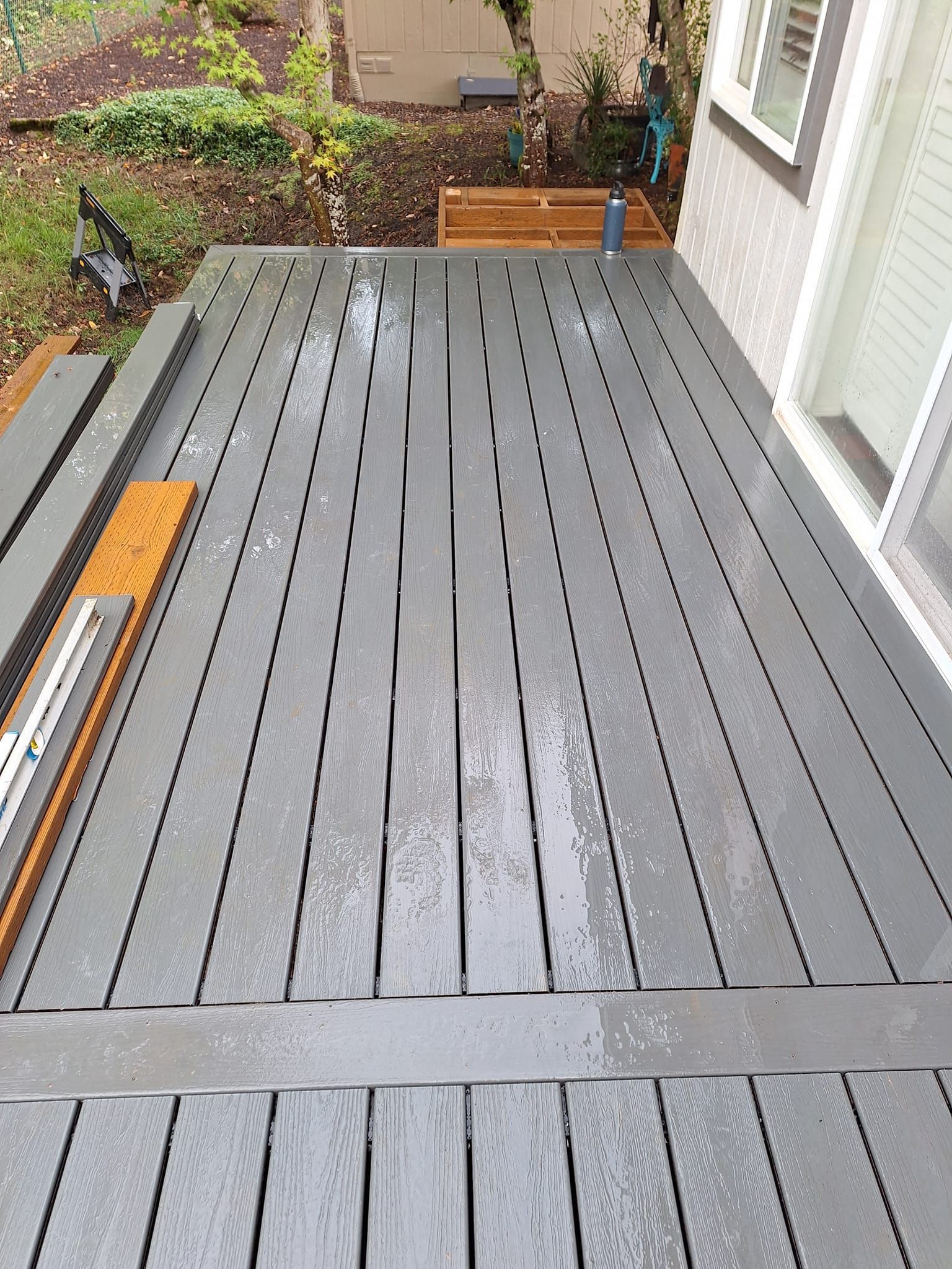 A gray wooden deck with a sliding glass door in the background.