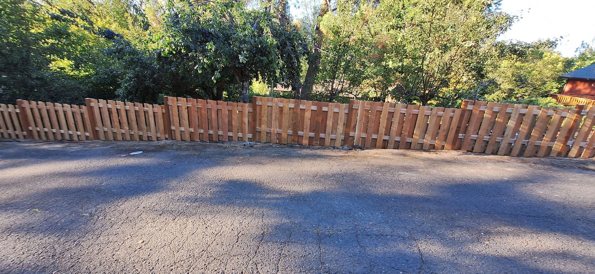 A wooden fence is sitting on top of a gravel road.