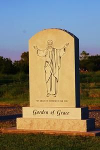 Gravestone monument engraved with Jesus and the words “Garden of Grace” at sunset