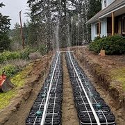Newly installed black drainage pipes in a trench beside a house during construction